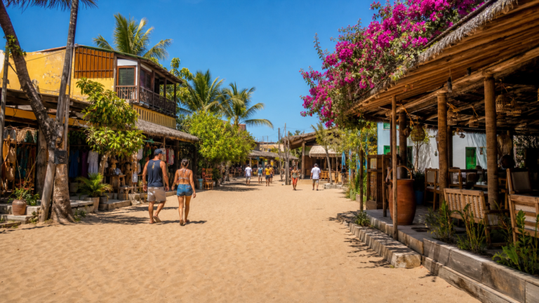 Rua de areia no centro da Vila de Jericoacoara com lojas rústicas.