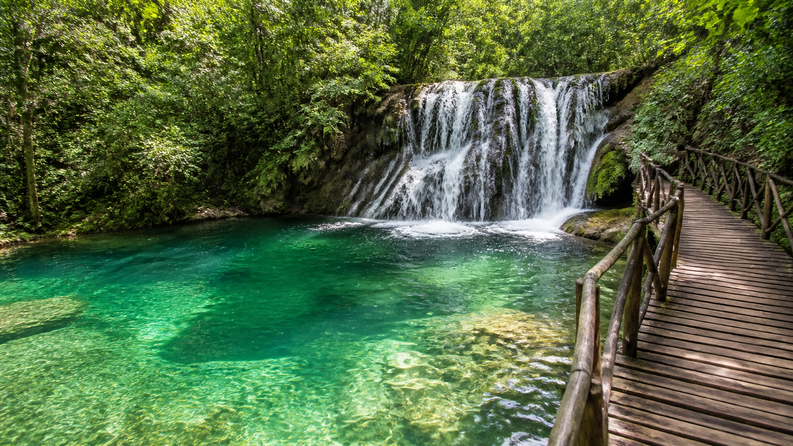 Scenic forest waterfall at Estância Mimosa in Bonito Brazil cascading into an emerald natural swimming pool