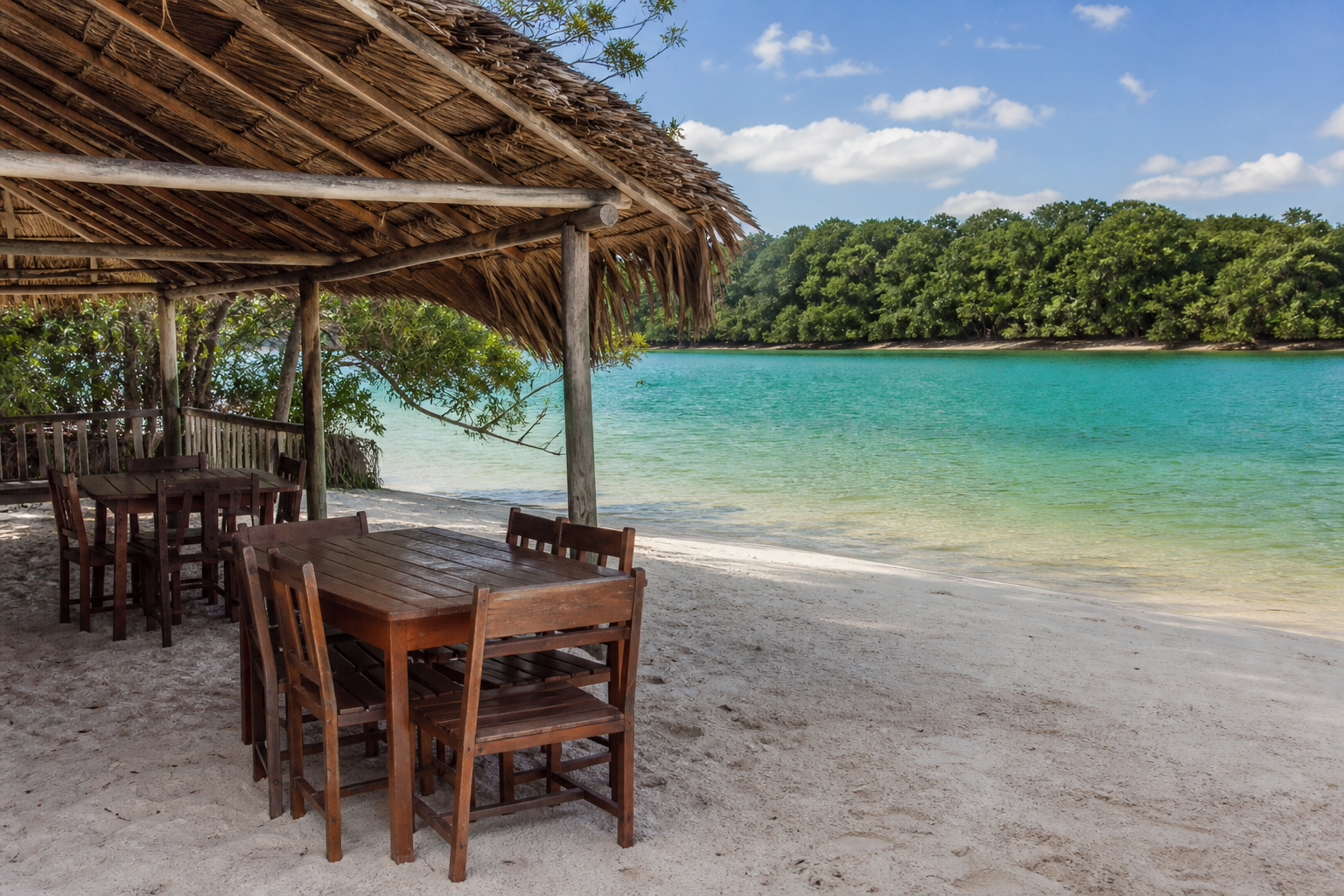 Rustic thatch-roofed beach kiosk barraca with dining tables on white sand in Alter do Chão