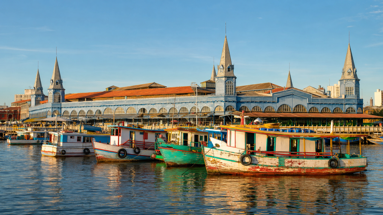 Historic 1901 blue iron turrets of Mercado Ver-o-Peso on the Guajará Bay waterfront in Belém with traditional wooden Amazon riverboats.