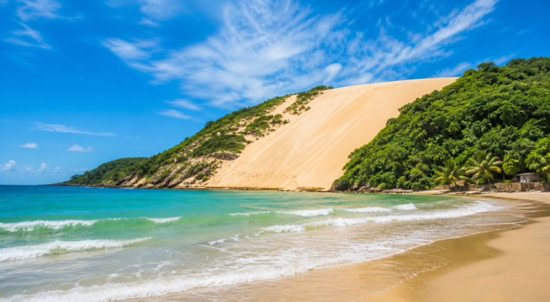 Scenic wide-angle view of the 107-meter Morro do Careca sand dune meeting the Atlantic Ocean at Ponta Negra beach in Natal, Brazil.