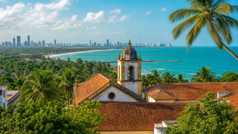 Panoramic view of historic Olinda with colonial church towers, coconut palms, and the Atlantic ocean