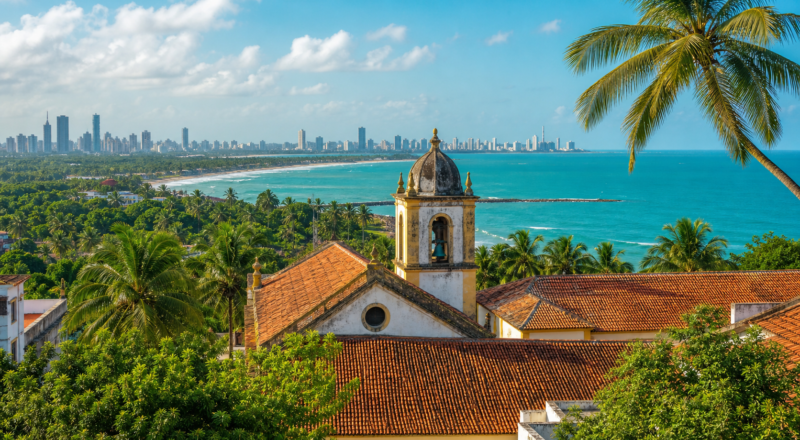 Panoramic view of historic Olinda with colonial church towers, coconut palms, and the Atlantic ocean