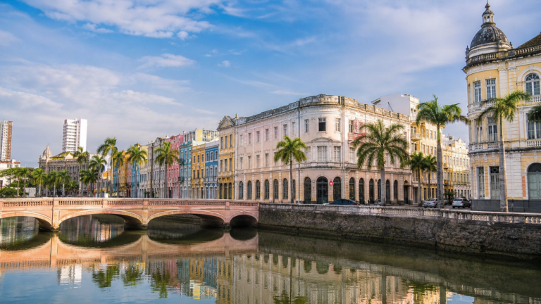 Historic bridges and colorful neoclassical row houses along Rua da Aurora reflecting in the Capibaribe River in Recife, Brazil.