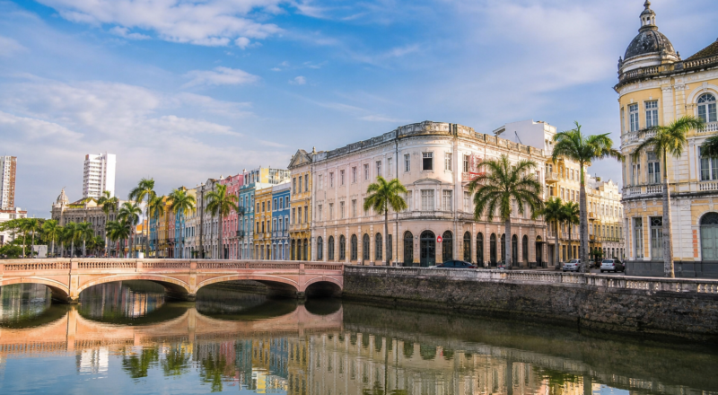 Historic bridges and colorful neoclassical row houses along Rua da Aurora reflecting in the Capibaribe River in Recife, Brazil.