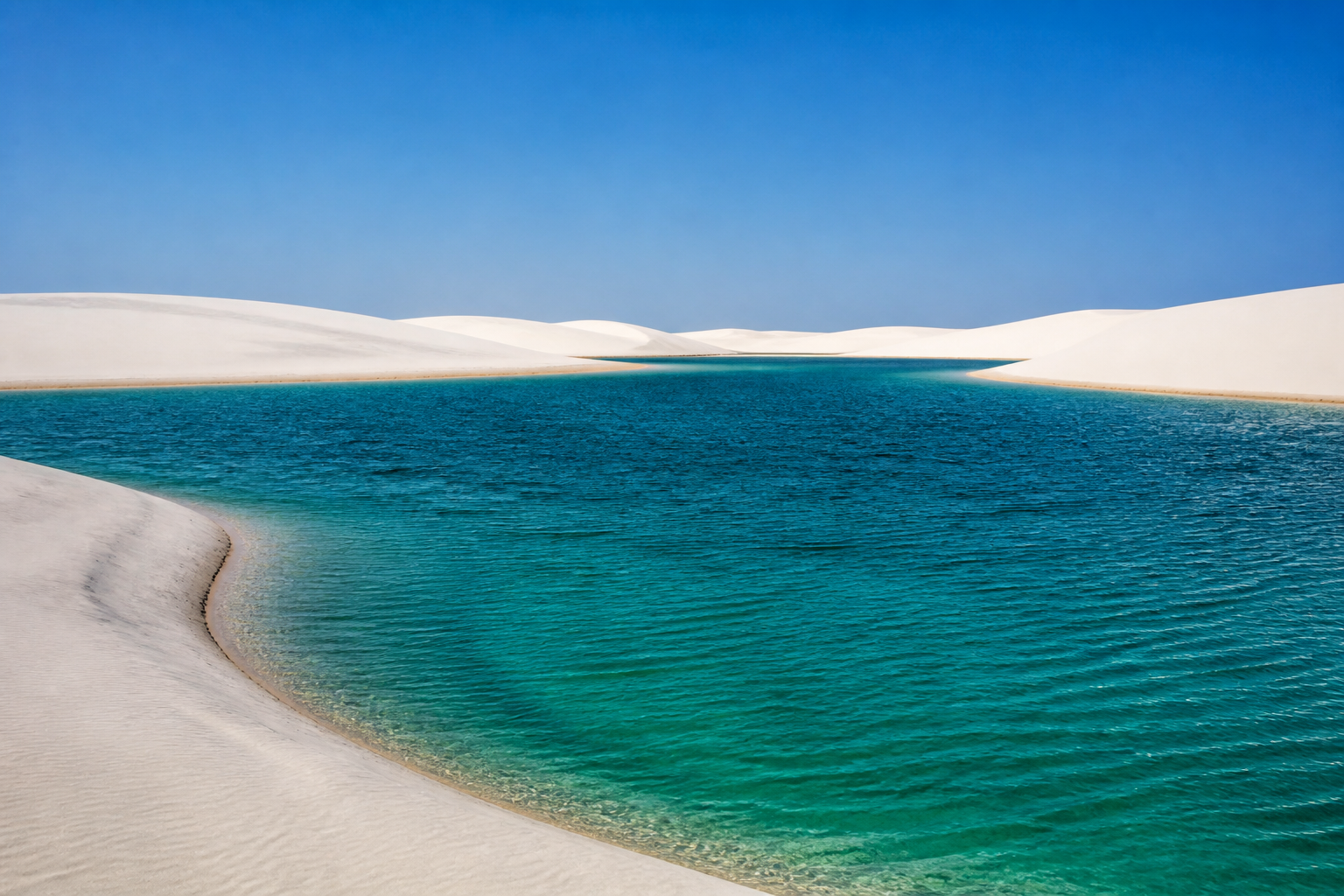 Expansive deep turquoise freshwater lagoon framed by white quartz sand dunes in Santo Amaro do Maranhão.