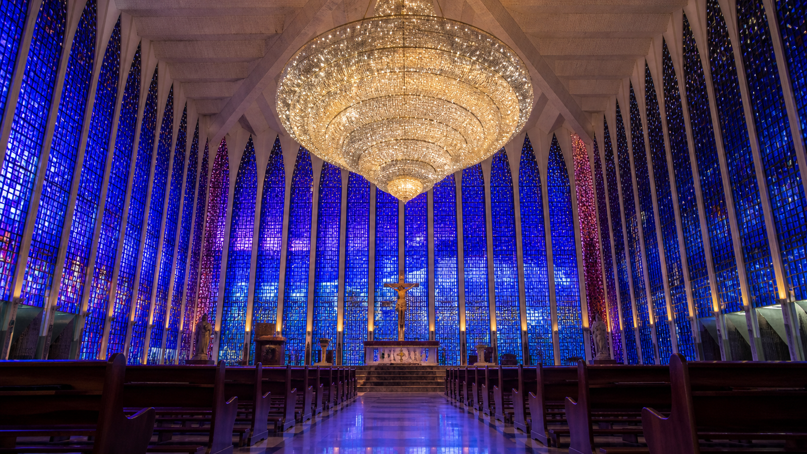 Interior of Santuário Dom Bosco glowing with vibrant blue and violet stained glass light and grand Murano chandelier