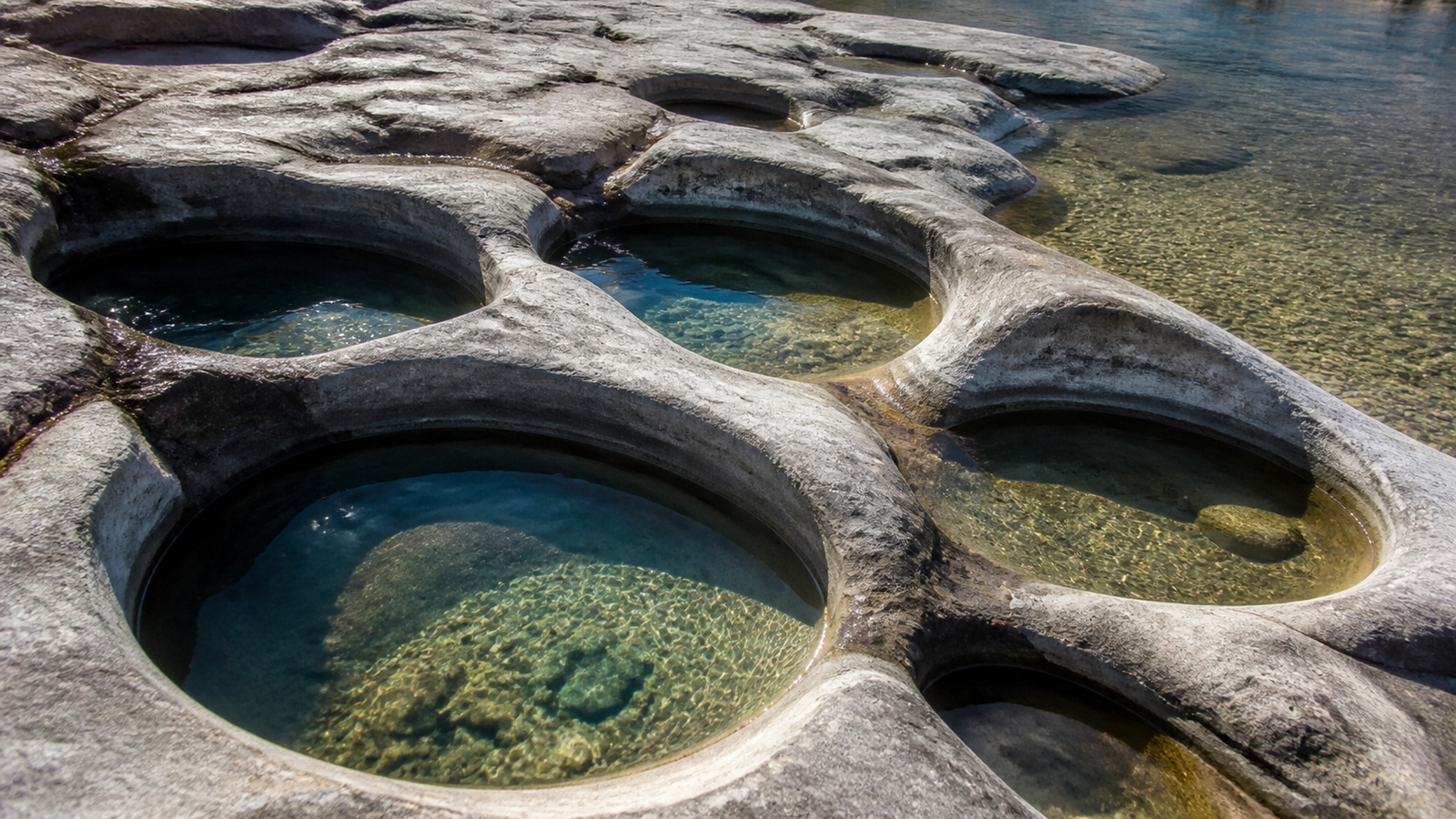Smooth circular rock cauldrons carved by river water at Vale da Lua