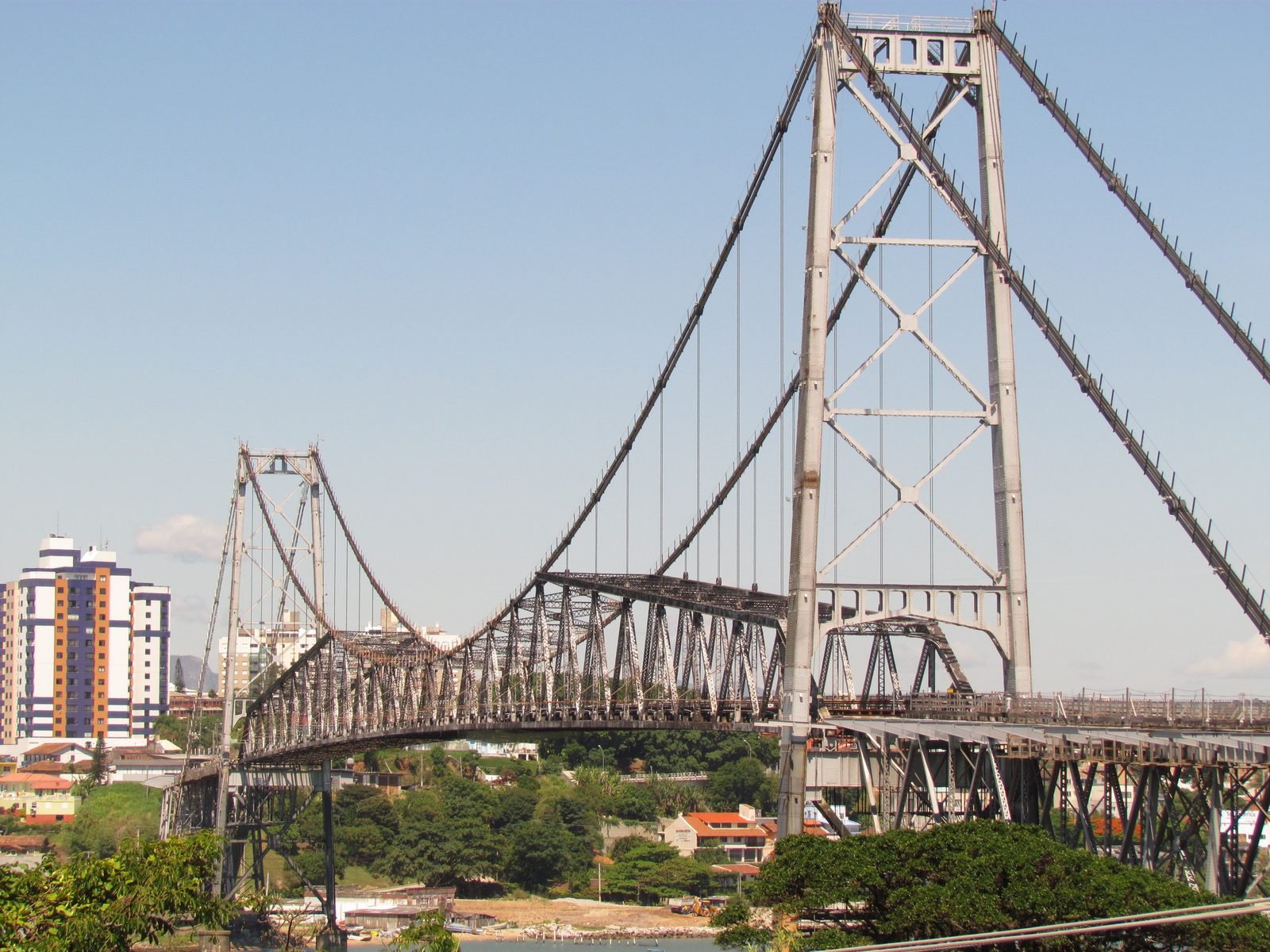 Hercílio Luz Bridge in Florianópolis, Brazil, a steel suspension bridge with two towers linking the island to the mainland, seen from the island side with downtown buildings