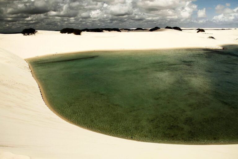 Lagoa de água verde e transparente cercada por dunas de areia branca no circuito da Lagoa Azul, em Barreirinhas, nos Lençóis Maranhenses