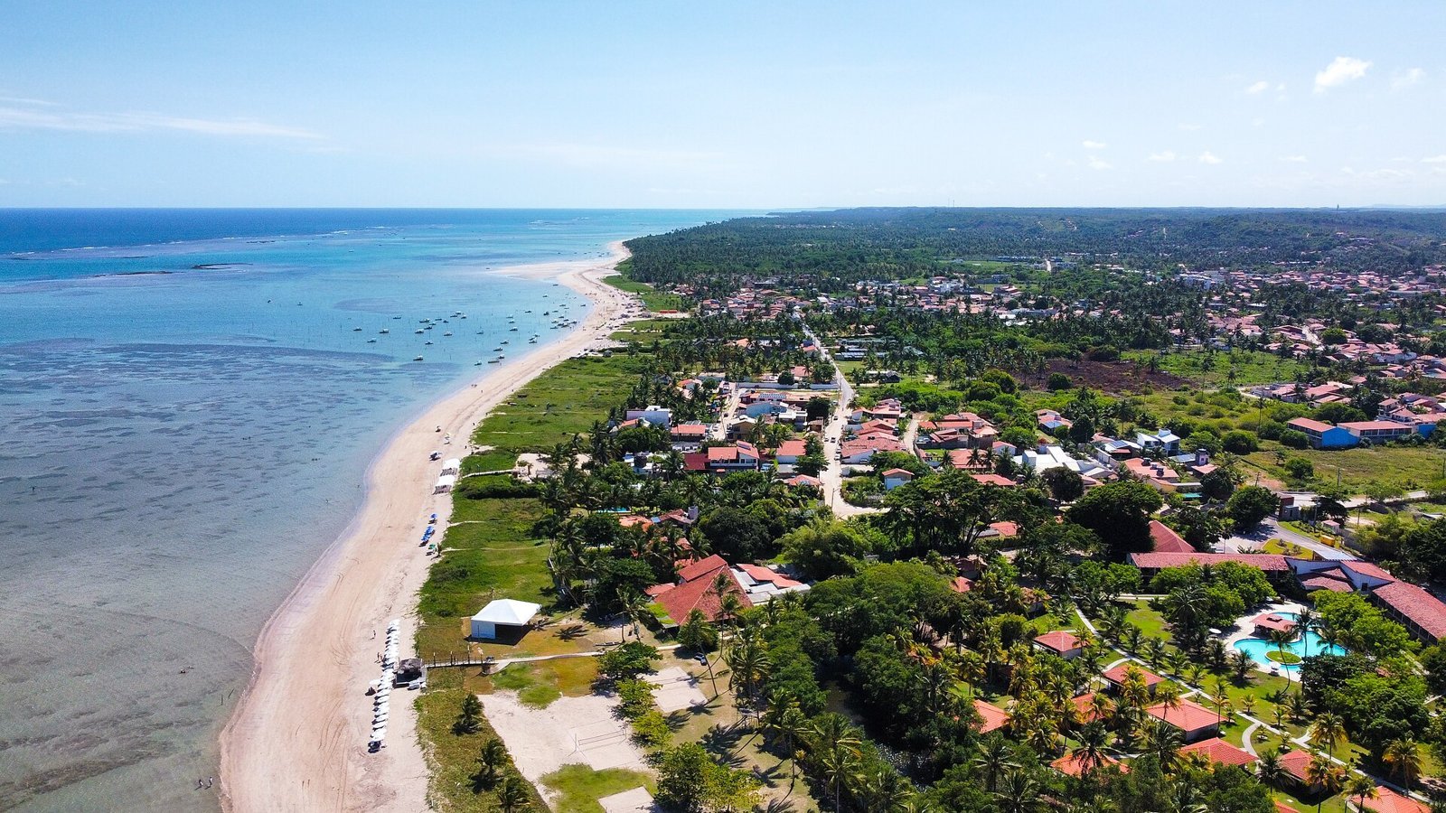 O que fazer em Maragogi: guia completo 2026 com piscinas naturais, marés, taxas, roteiro e onde ficar 4 Vista aérea da Praia do Porto da Rua, em São Miguel dos Milagres, com mar em tons de verde e azul, recifes escuros sob a água, faixa de areia e coqueiral