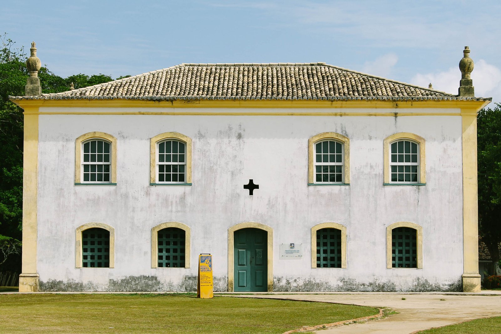Fachada branca de dois andares da Casa de Câmara e Cadeia, na Cidade Histórica de Porto Seguro (BA), com janelas e portas verdes e gramado em frente
